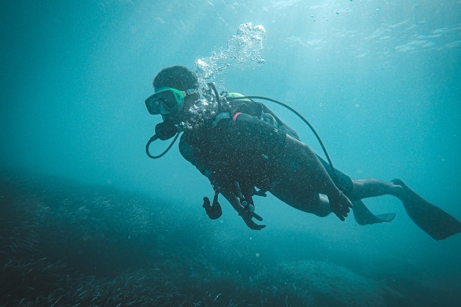 Scuba diver in cold dark water with school of fish